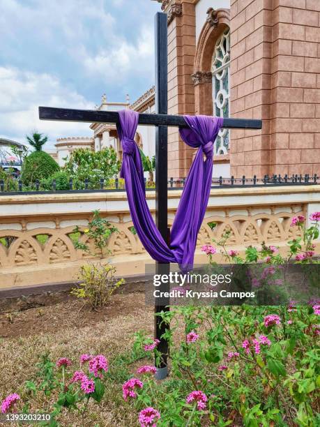 purple cloth draped on wooden cross at public park in costa rica - christian campos stock pictures, royalty-free photos & images