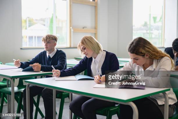 students taking educational exam in secondary classroom - school exam stockfoto's en -beelden