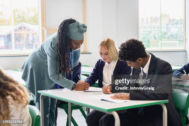 educadora madura que ayuda a los estudiantes de secundaria en clase - help palabra en inglés fotografías e imágenes de stock