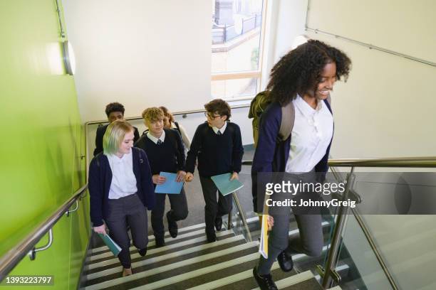 estudiantes de secundaria subiendo escaleras en edificio escolar - british culture walking fotografías e imágenes de stock