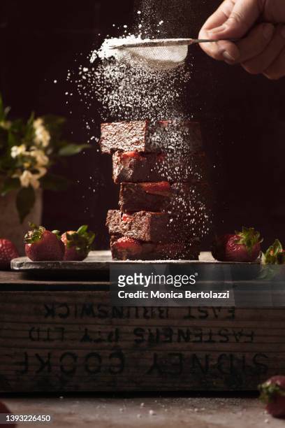 chocolate and strawberry cake, being sifted with icing sugar. with human hand - party pies imagens e fotografias de stock