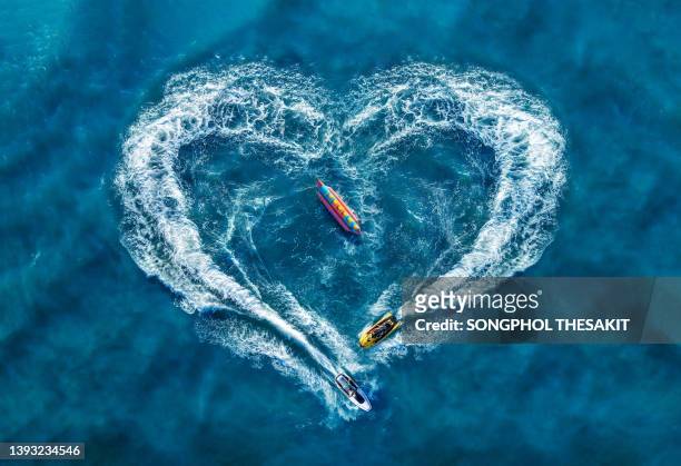 aerial view/waves from the jet skis circling in a beautiful heart shape in the sea. - jet ski - fotografias e filmes do acervo