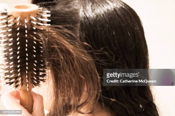mixed-race teenage girl blow dries her hair at home - blow drying hair stock pictures, royalty-free photos & images