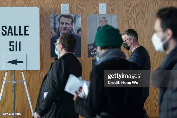 French citizen walk pass by posters of candidates Emmanuel Macron and Marine Le Pen as they go to vote in the second round of France's presidential...