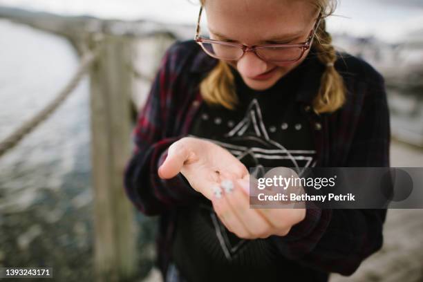 neurodiverse teen girl with glasses and braided pigtails  looks at ladybug in her hand - autismus stock pictures, royalty-free photos & images