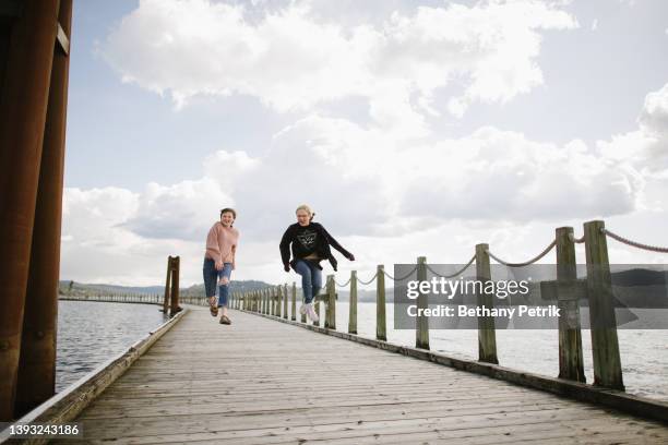 teens skip on pier - skip queue stock pictures, royalty-free photos & images