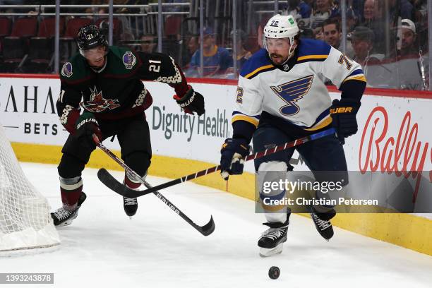 Justin Faulk of the St. Louis Blues skates with the puck ahead of Loui Eriksson of the Arizona Coyotes during the second period of the NHL game at...