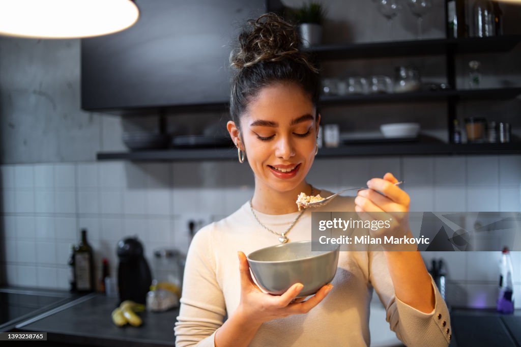 A young woman eats oatmeal