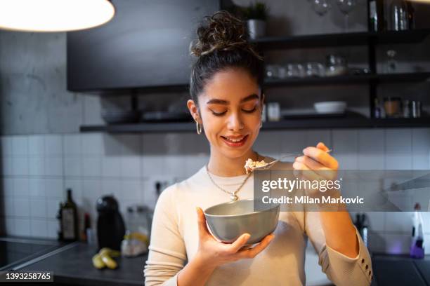 a young woman eats oatmeal - swallow imagens e fotografias de stock