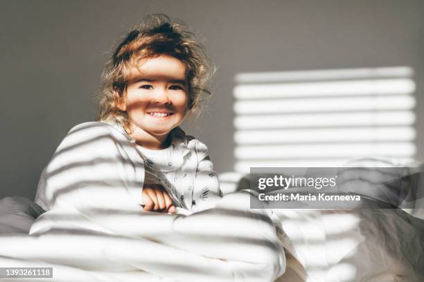 happy baby girl smiling while lying on bed. - baby light stock-fotos und bilder