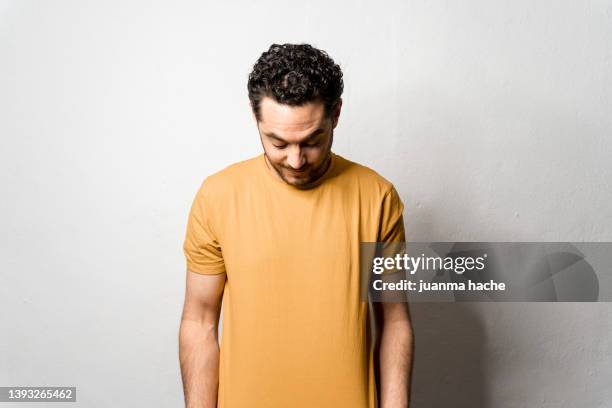 man dressed in yellow t-shirt looking playfully at his messy hair. - plain t shirt stock pictures, royalty-free photos & images