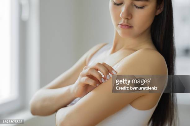 young woman scratching her arm - mosquito stock pictures, royalty-free photos & images