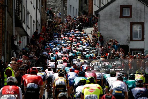 General view of the peloton passing through the Côte de Saint-Roch in Houffalize City while fans cheer during the 108th Liege - Bastogne - Liege 2022...