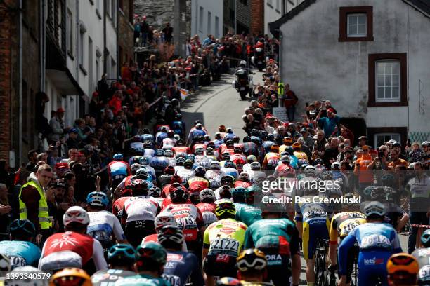 General view of the peloton passing through the Côte de Saint-Roch in Houffalize City while fans cheer during the 108th Liege - Bastogne - Liege 2022...