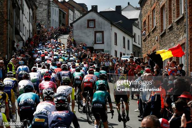 General view of the peloton passing through the Côte de Saint-Roch in Houffalize City while fans cheer during the 108th Liege - Bastogne - Liege 2022...