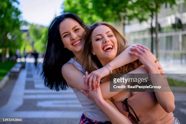coppia di giovani donne che si abbracciano in una giornata estiva in città - summer university day 2 foto e immagini stock