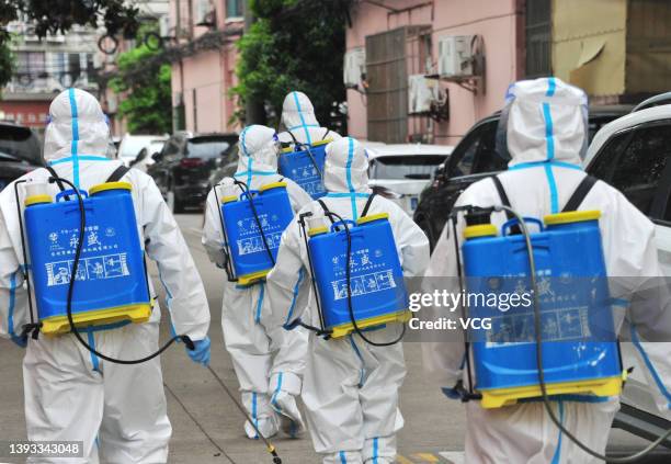 Volunteers wearing personal protective equipment disinfect a residential community at Yangpu district during the phased lockdown triggered by the...