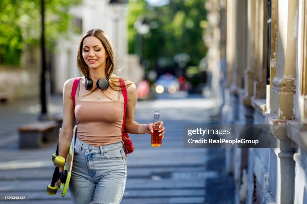 Young Woman walking with skateboard in hand on city street