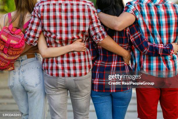 rearview shot of a group of unrecognizable young friends walking with their arms around each other in the citygroup of attractive teenage students walking from university. - fun lovers unite stock pictures, royalty-free photos & images