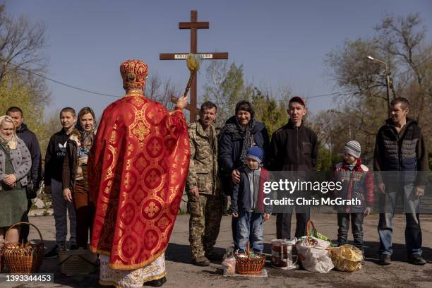 People wait with their Easter baskets to be blessed by a priest during an Easter Sunday service outside a church on April 24, 2022 in Zaporizhzhia,...