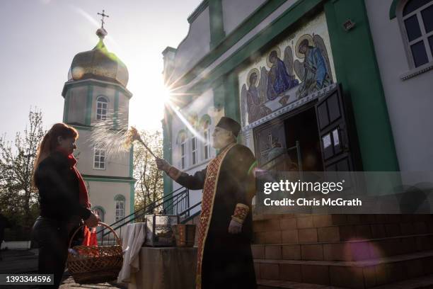 Woman stands with her easter basket to be blessed by a priest during an Easter Sunday service outside a church on April 24, 2022 in Zaporizhzhia,...