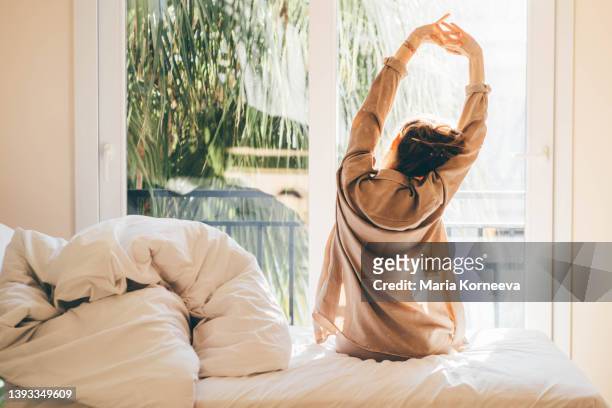 woman waking up and relaxing near window at home. - wakker worden stockfoto's en -beelden
