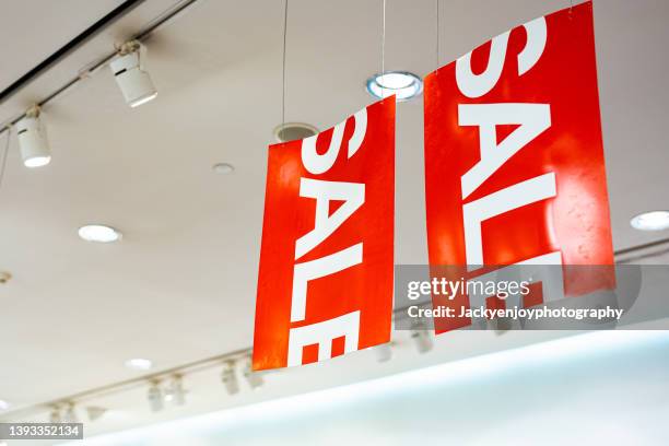red sale sign hanging from ceiling at the store in shopping mall. - espositore foto e immagini stock