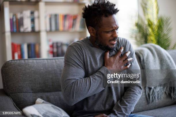 胸の痛みに苦しんでいて、心臓の部分に触れているストレスのある男性のクローズアップ写真 - 心臓病 ストックフォトと画像