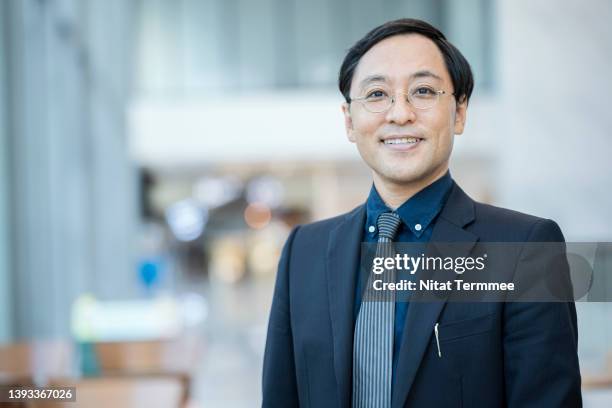 portrait of confidence male japanese entrepreneur standing in convention centre. he is trader in providing products, service and support to his customers. - male portrait suit and tie 40 year old stock pictures, royalty-free photos & images