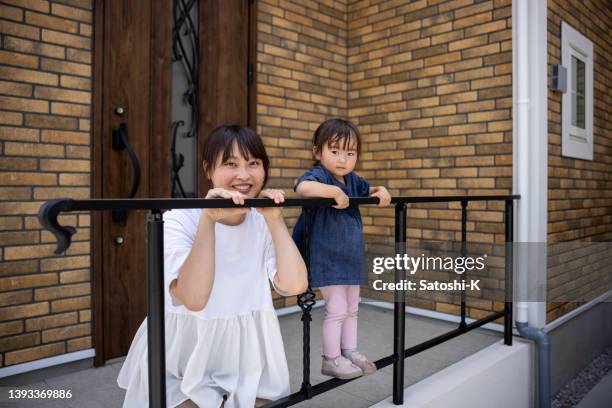 portrait of mother with her little daughter at the entrance of the house - brick house door stock pictures, royalty-free photos & images