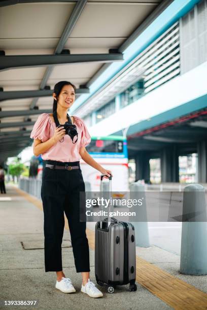 tourist looking away while holding camera during vacation - airport bus stock pictures, royalty-free photos & images