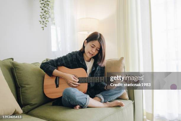 garota tocando guitarra na sala. músico praticando música em instrumento de corda - string instrument - fotografias e filmes do acervo