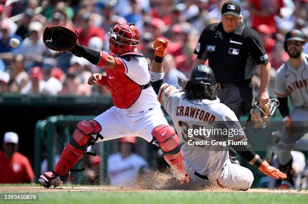 Brandon Crawford of the San Francisco Giants scores in the first inning ahead of the throw to Keibert Ruiz of the Washington Nationals at Nationals...