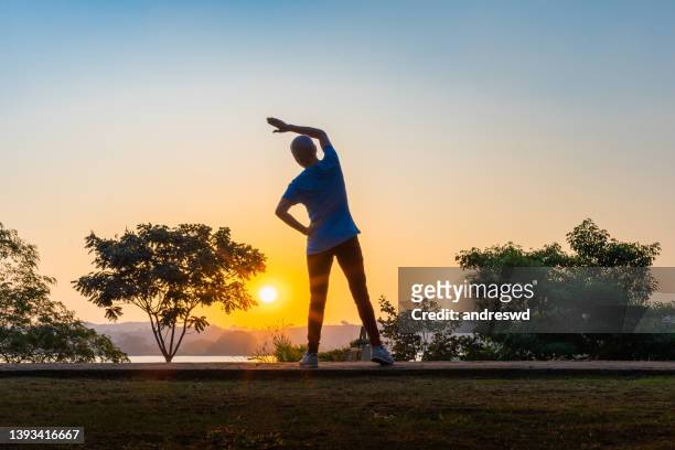 krebspatientin frau - woman stretching sunset stock-fotos und bilder