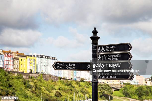 bilingual welsh english langauge street sign with iconic colourful terraced houses in background, tenby, uk - multilingual stock pictures, royalty-free photos & images