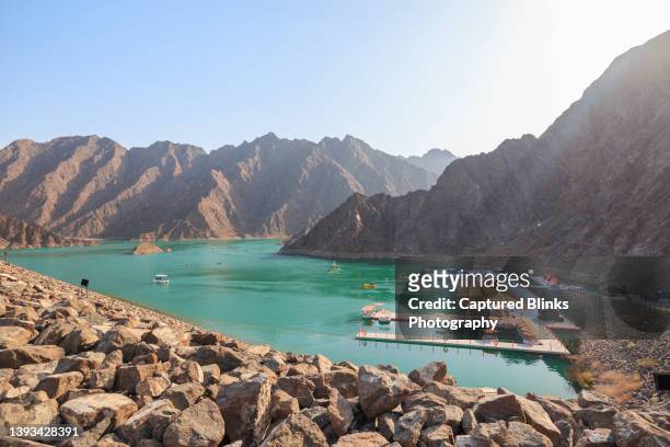 hatta dam in uae with rocky mountain ranges and kayak boats in lake - perzische golfstaten stockfoto's en -beelden