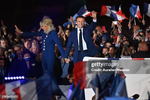 France's centrist incumbent president Emmanuel Macron and his wife Brigitte Macron acknowledge voters in front of the Eiffel Tower after after giving...