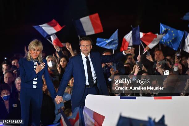 France's centrist incumbent president Emmanuel Macron and his wife Brigitte Macron acknowledge voters in front of the Eiffel Tower after after giving...