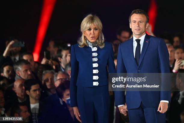 France's centrist incumbent president Emmanuel Macron and his wife Brigitte Macron acknowledge voters in front of the Eiffel Tower after after giving...