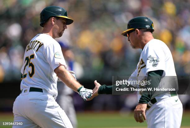 Stephen Piscotty of the Oakland Athletics is congratulated by third base coach Darren Bush on his two-run home run against the Texas Rangers in the...