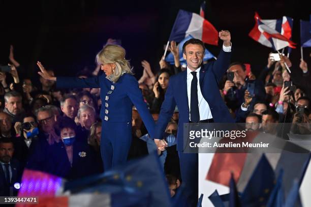France's centrist incumbent president Emmanuel Macron and his wife Brigitte Macron acknowledge voters in front of the Eiffel Tower after after giving...