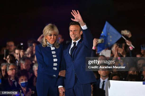 France's centrist incumbent president Emmanuel Macron and his wife Brigitte Macron acknowledge voters in front of the Eiffel Tower after after giving...