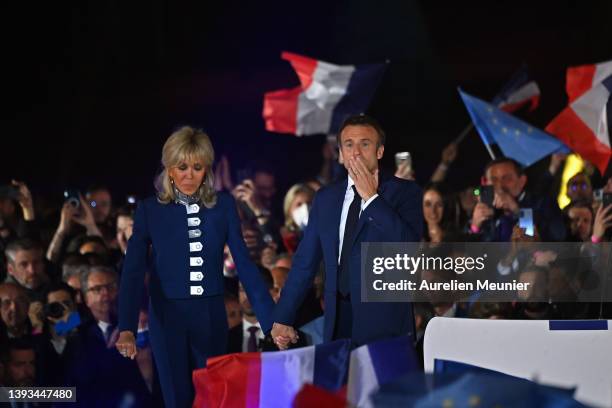 France's centrist incumbent president Emmanuel Macron and his wife Brigitte Macron acknowledge voters in front of the Eiffel Tower after after giving...