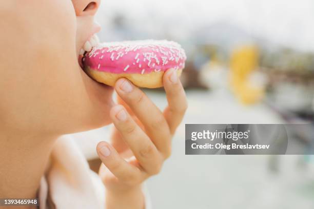 overweight hungry woman biting donut close up. concept of unhealthy fast food eating. unrecognizable person. - fat people eating donuts - fotografias e filmes do acervo