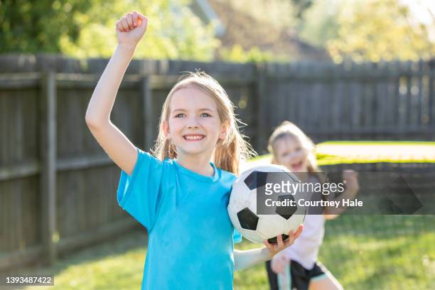 adorable elementary age sisters playing soccer together in backyard at home - soccer goalkeeper stock pictures, royalty-free photos & images