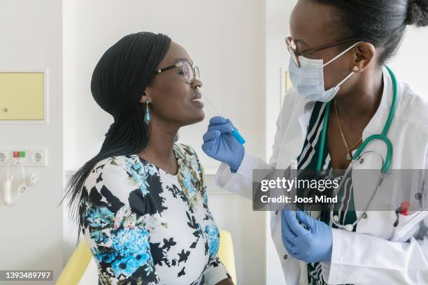 female doctor taking a nasal swab sample test of mature woman - mrsa stock pictures, royalty-free photos & images