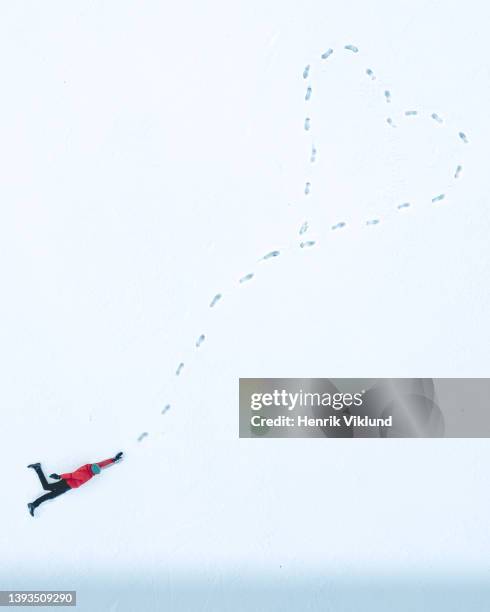 person hanging on to a heart in snow - photo illustration by stock-fotos und bilder