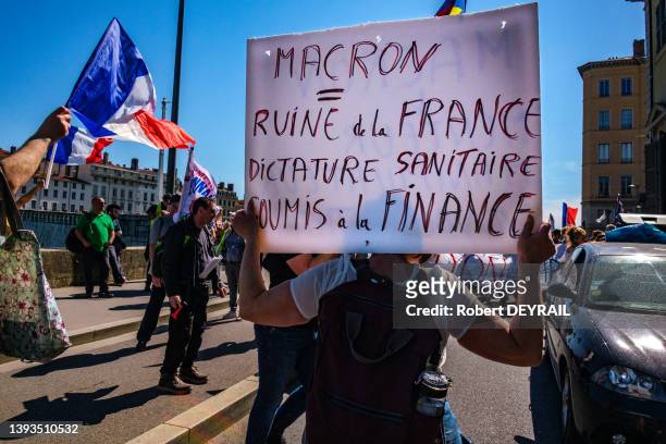 Drapeau français et manifestante avec une pancarte 'MACRON = RUINE DE LA FRANCE, DICTATEUR SANITAIRE SOUMIS À LA FINANCE' lors d'une manifestation...