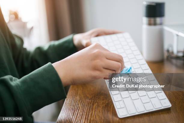 man hands cleaning the surface of computer keyboard - antiseptic wipe stockfoto's en -beelden