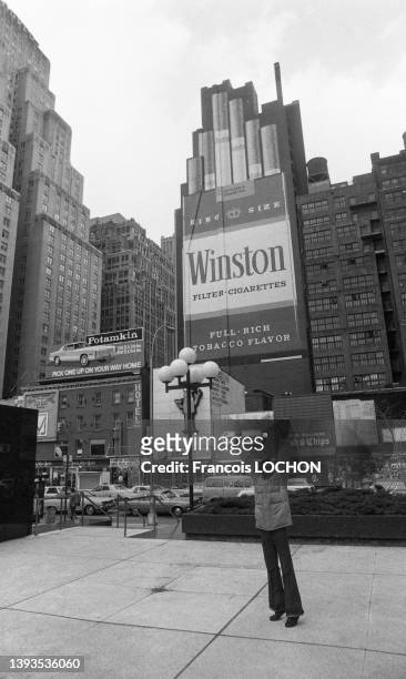 Jeune homme de couleur habillé d'un blouson et d'un pantalon patte d'éléphant levant les bras et publicité pour des cigarettes "Winston" en mai 1978...